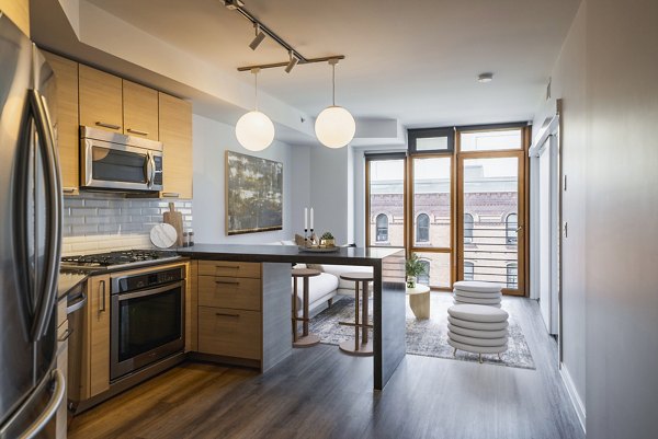 Modern kitchen with granite countertops and stainless steel appliances in The Goodwin Apartments