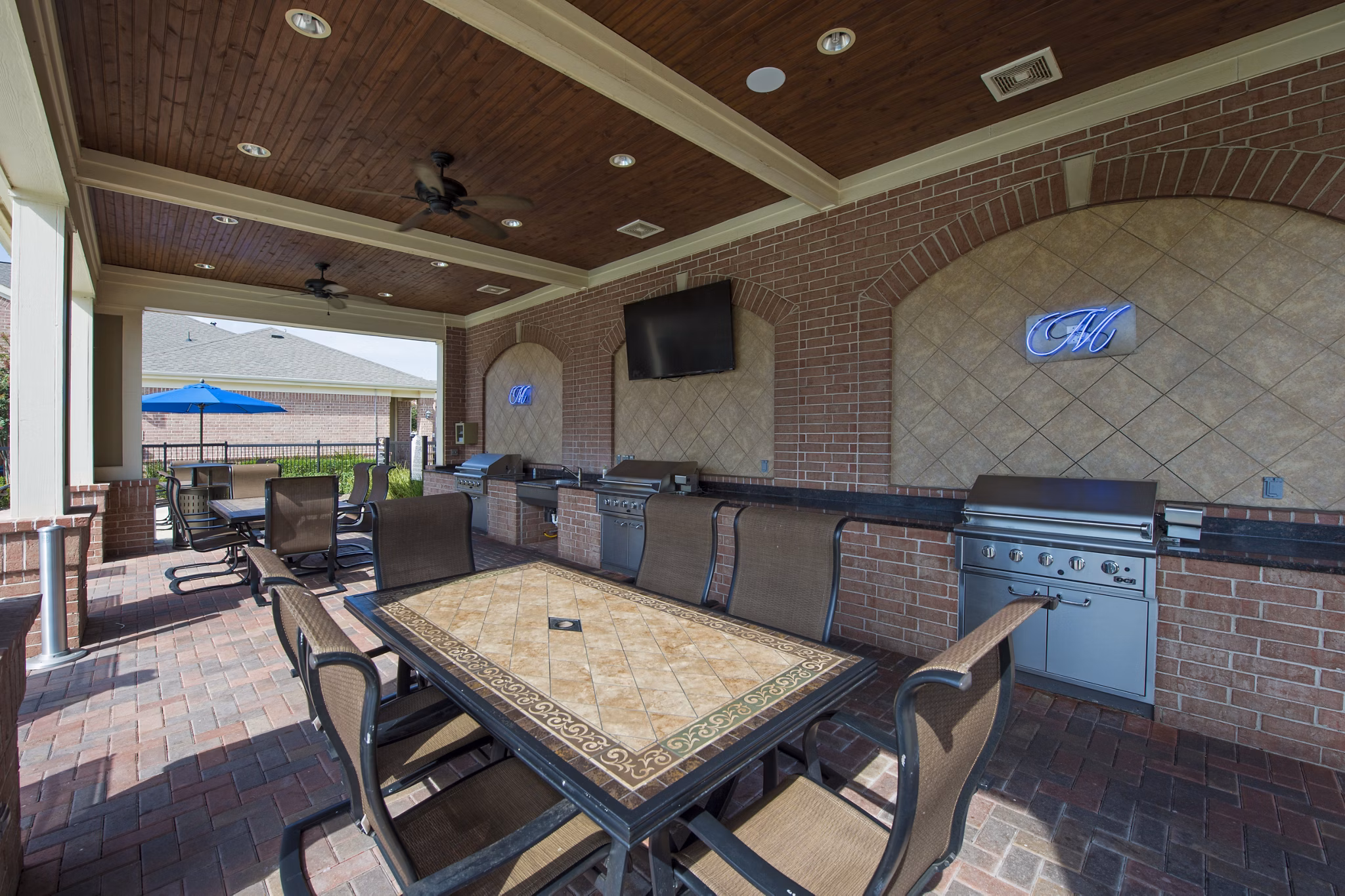 Outdoor BBQ grill area at Montage at Cinco Ranch Apartments featuring modern seating and lush landscaping in Katy, Texas