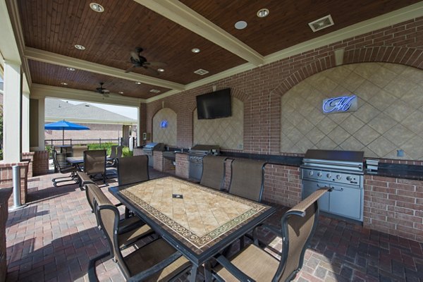 Outdoor BBQ grill area at Montage at Cinco Ranch Apartments featuring modern seating and lush landscaping in Katy, Texas