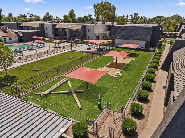 Fenced dog park with agility equipment at Highland Park Apartments