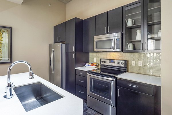 Modern kitchen featuring stainless steel appliances and granite countertops at Elan Med Center Apartments