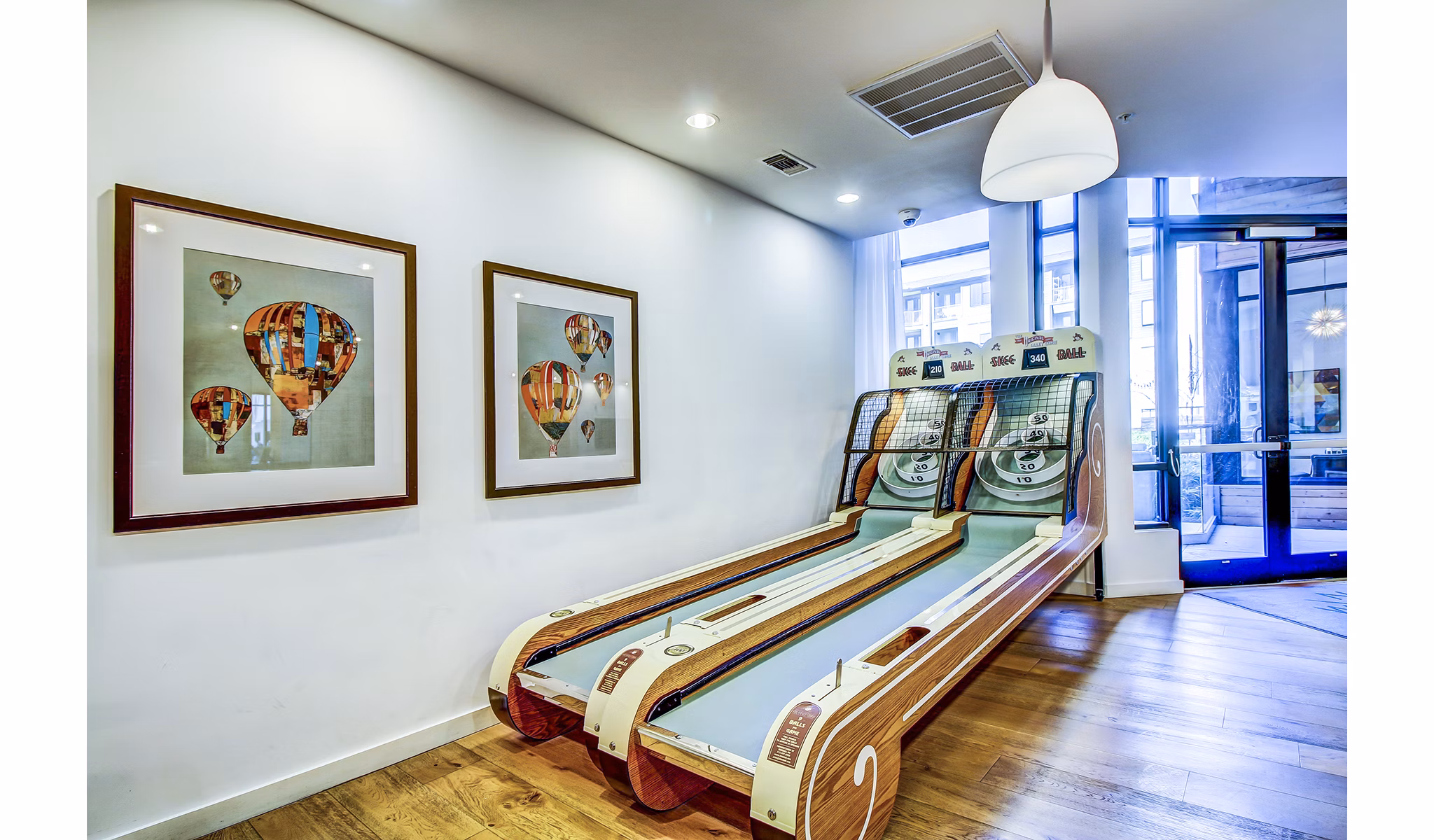 Skee-ball game setup with framed hot air balloon pictures in a vibrant recreational room