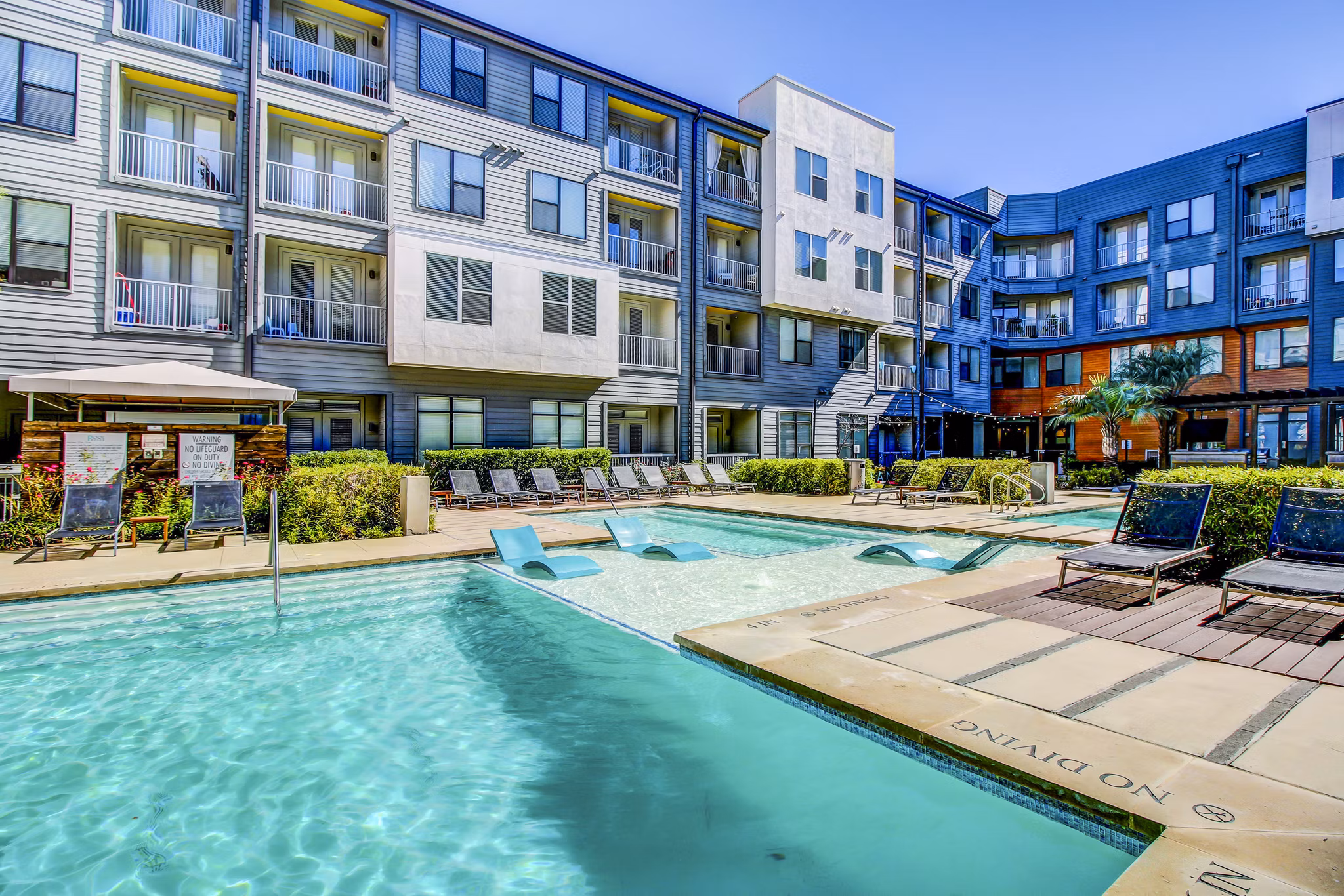 Resort-style pool area with lounging chairs at Elan East Apartments