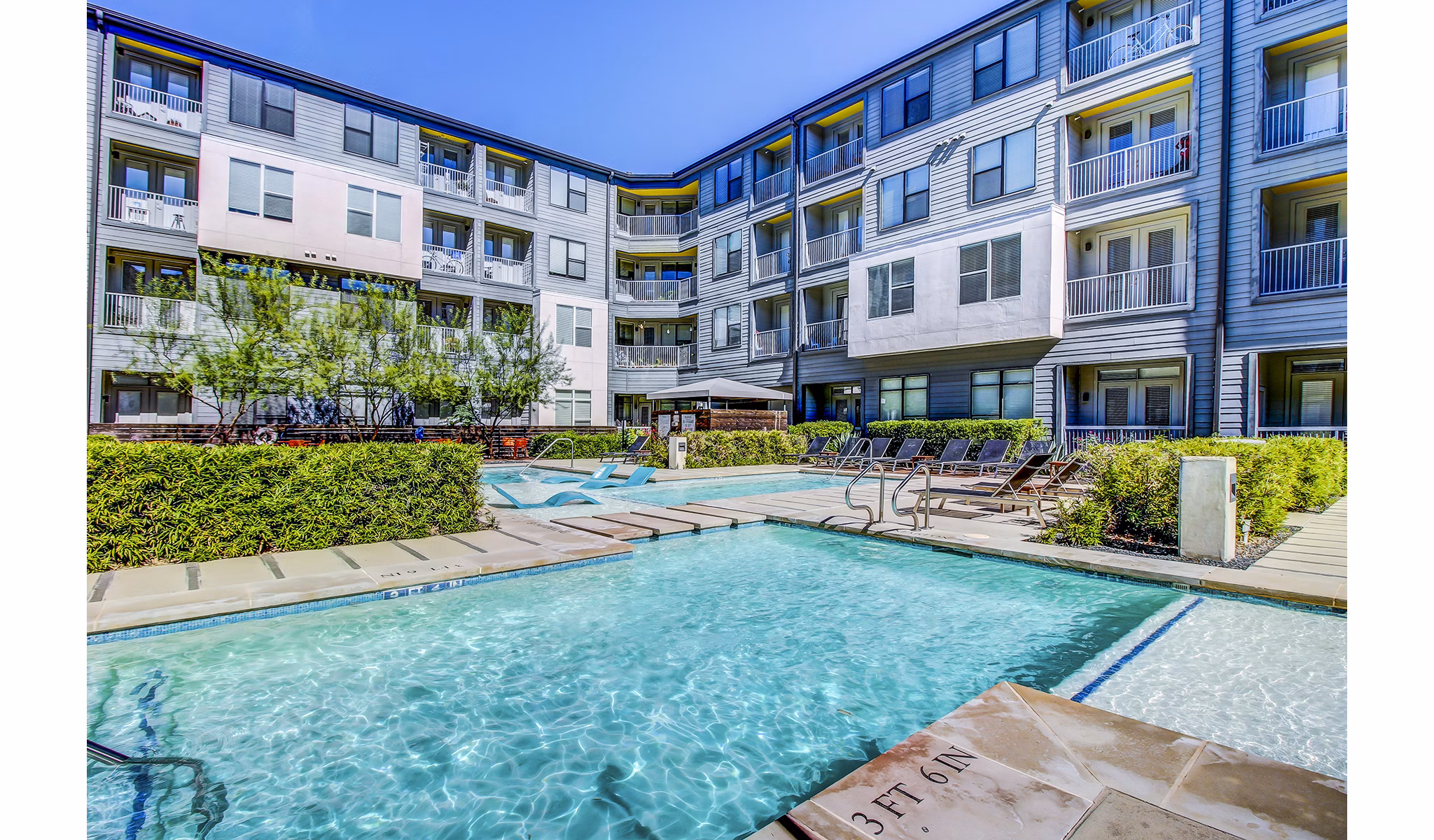 Modern pool with sun loungers at Elan East Apartments, offering luxury outdoor living in a relaxing environment