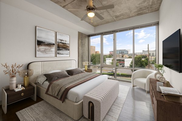 Cozy bedroom with contemporary design at The Devon Four25 Apartments, featuring luxurious bedding and ample natural light for a modern living experience