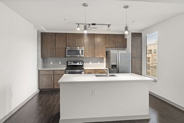 Modern kitchen with stainless steel appliances and granite countertops at The Devon Four25 Apartments