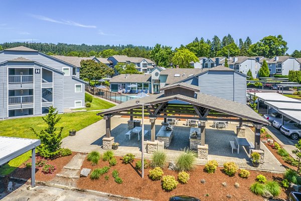 Outdoor grill area with cozy seating at Avana at Happy Valley Apartments, ideal for social gatherings and relaxation amidst lush surroundings