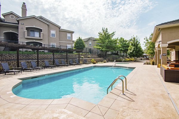 Resort-style pool surrounded by lush landscaping at Estancia at City Center Apartments, offering luxury living and relaxation