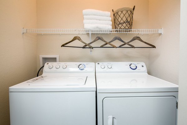 Laundry room with modern machines at The Retreat at Trinity Apartments