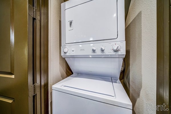 Laundry room featuring modern appliances at The Millennium Waterway apartments
