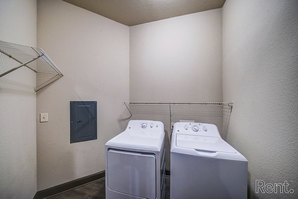 Laundry room with modern appliances and ample folding space at The Millennium Waterway apartments in The Woodlands