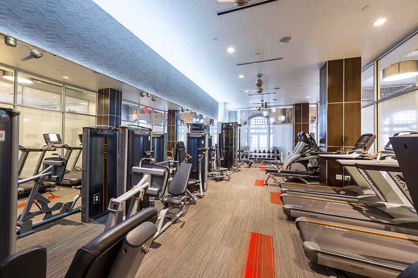The Rice Apartments: Modern fitness center with state-of-the-art equipment and bright lighting for resident wellness