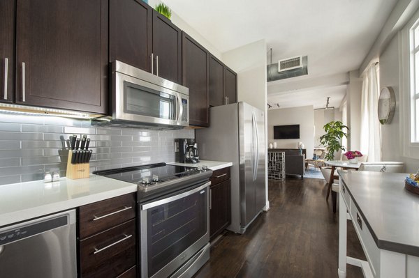 Modern kitchen with stainless steel appliances and stone countertops in The Rice Apartments, luxury living in the heart of the city
