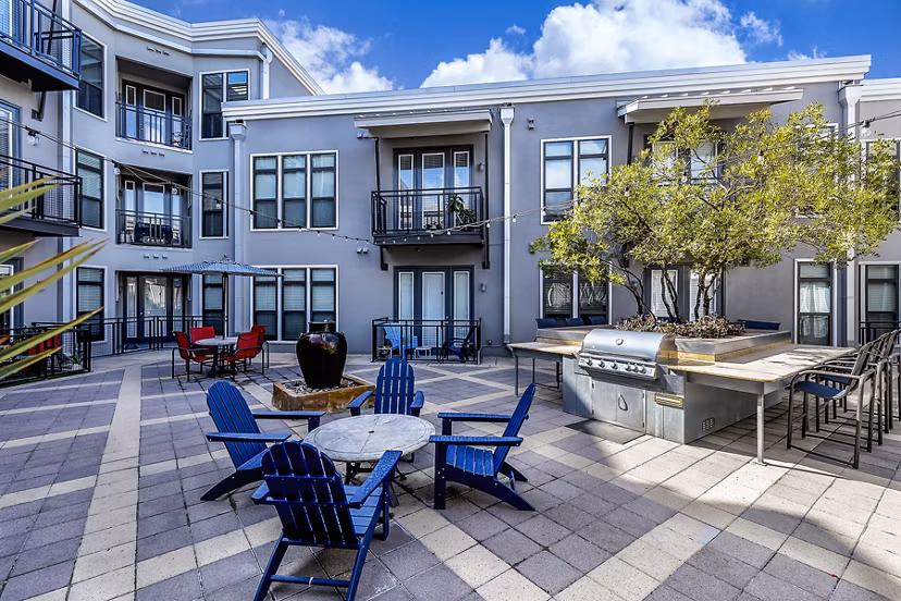 Outdoor grill area with seating at 5th Street Commons Apartments, perfect for social gatherings and dining al fresco
