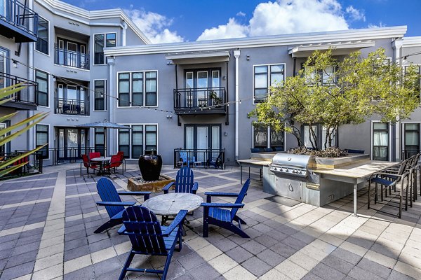Outdoor grill area with seating at 5th Street Commons Apartments, perfect for social gatherings and dining al fresco