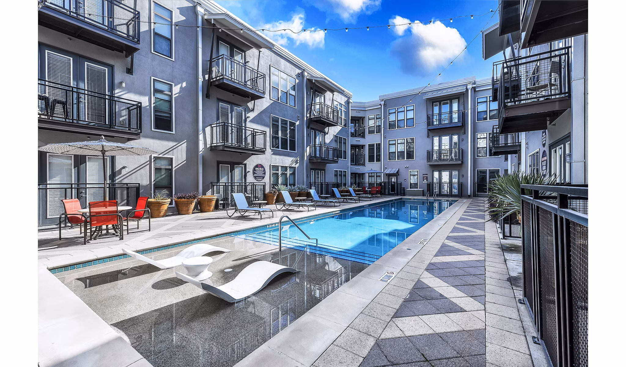 Spacious outdoor pool area at 5th Street Commons Apartments with sun loungers and scenic views