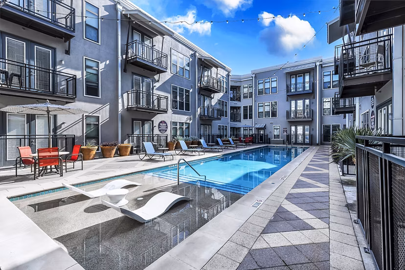 Spacious outdoor pool area at 5th Street Commons Apartments with sun loungers and scenic views