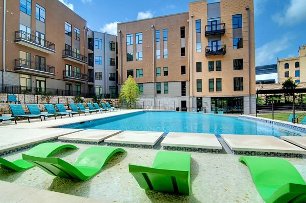 Resort-style pool with lounge chairs at River House Apartments, offering relaxation and leisure in a luxury setting