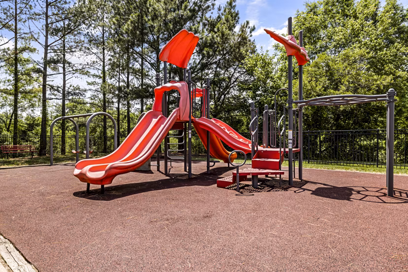 Children's playground at Columns at Wakefield featuring slides and swings, luxury family amenities in this Greystar community
