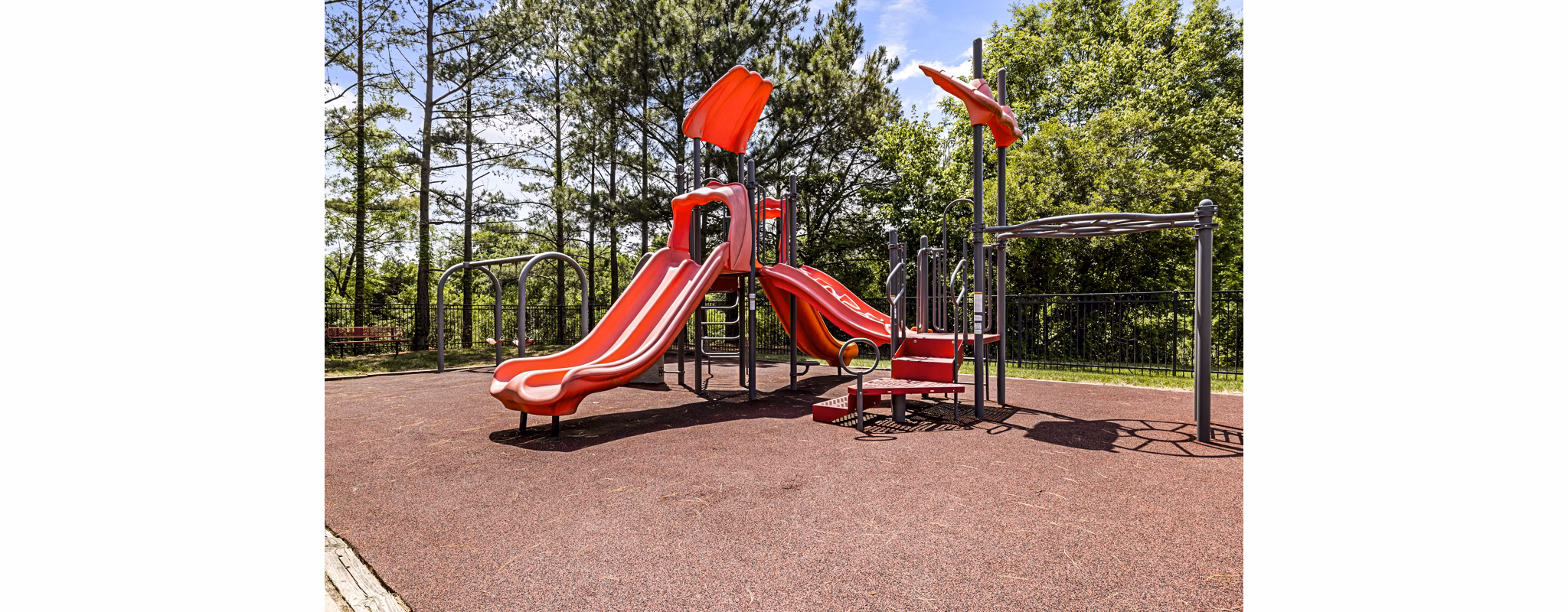Children's playground at Columns at Wakefield featuring slides and swings, luxury family amenities in this Greystar community