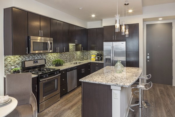 Modern kitchen with sleek finishes and island seating in One Lakes Edge apartments, ideal for luxury living