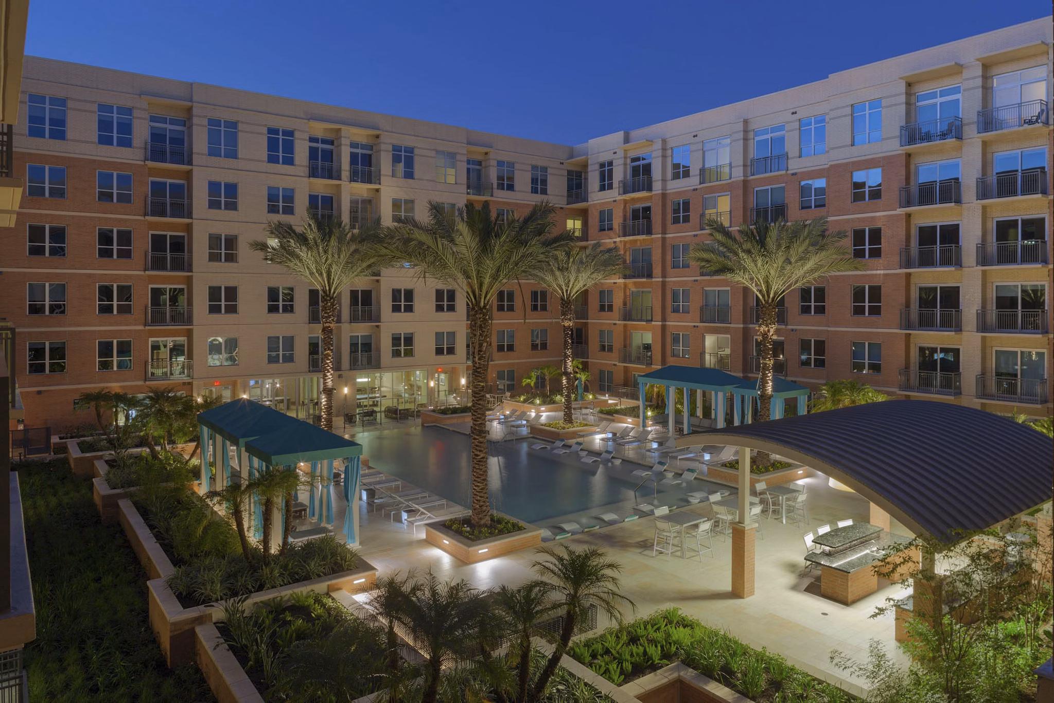 Luxurious pool area with loungers at One Lakes Edge, offering relaxation and stunning waterfront views for residents
