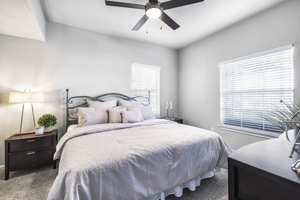 Bedroom with contemporary decor at Villages at Turtle Rock Apartments featuring large windows and cozy ambiance