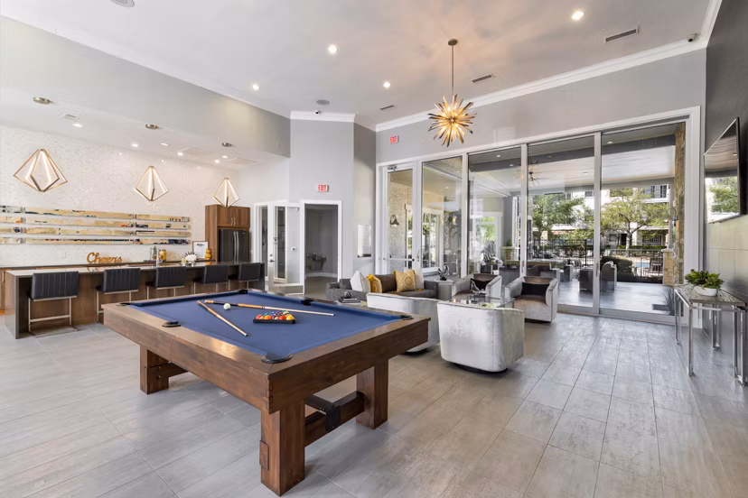 Game room with pool table and large screens at Villages at Turtle Rock Apartments