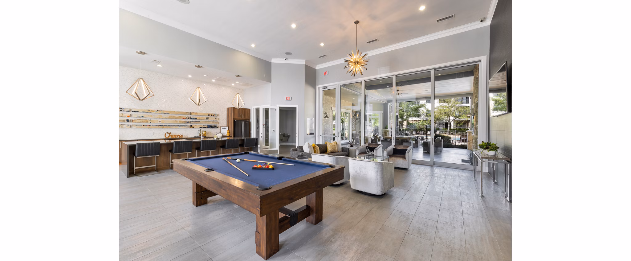 Game room with pool table and large screens at Villages at Turtle Rock Apartments