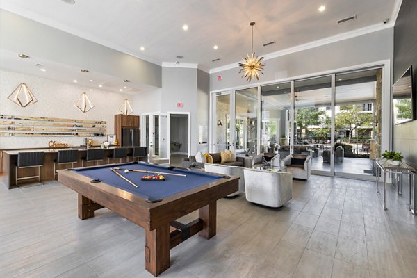 Game room with pool table and large screens at Villages at Turtle Rock Apartments