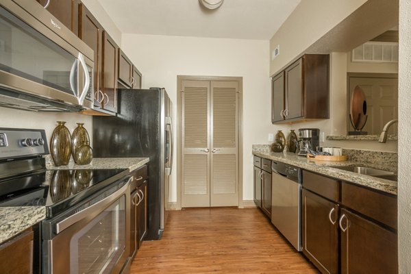 Kitchens featuring granite countertops and stainless steel appliances at Deerwood Apartments