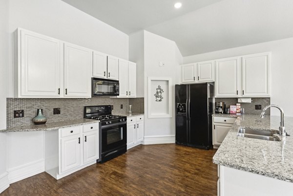 Modern kitchen with stainless steel appliances and granite countertops in Towns of Chapel Hill Apartments