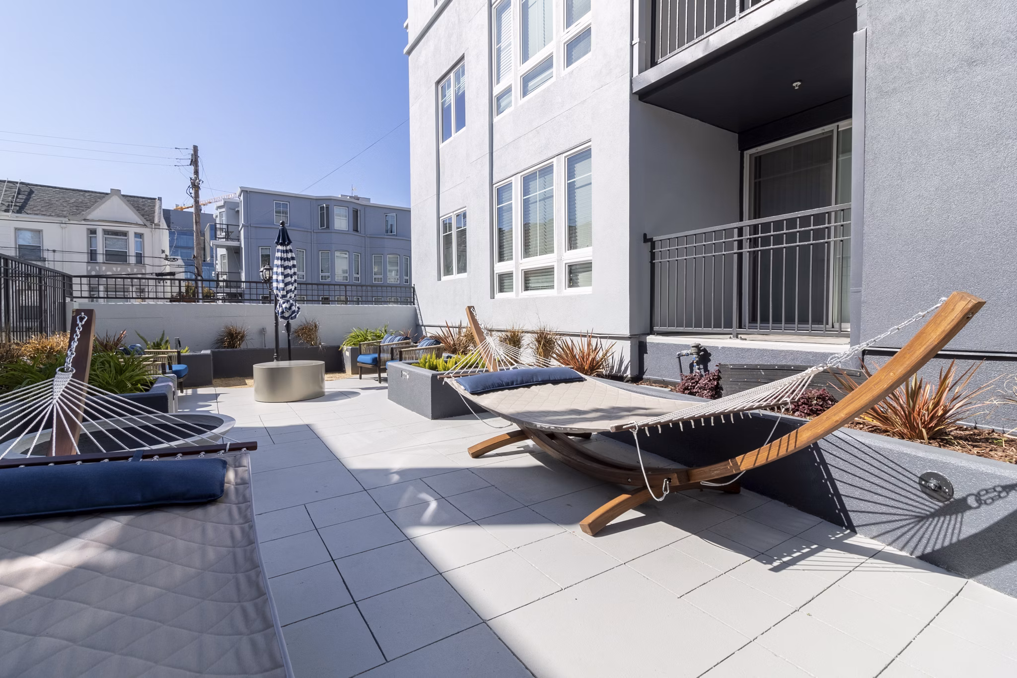 Sunlit patio at Hillside Village Apartments featuring modern outdoor seating and greenery