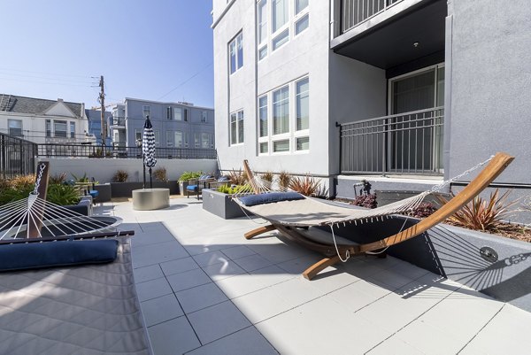 Sunlit patio at Hillside Village Apartments featuring modern outdoor seating and greenery