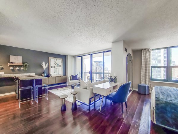 Bright living room with contemporary decor at One Superior Place Apartments, featuring large windows and cozy seating area