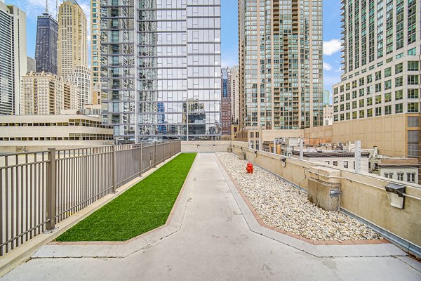 Dog play area at One Superior Place Apartments with lush greenery and agility equipment for residents and their pets