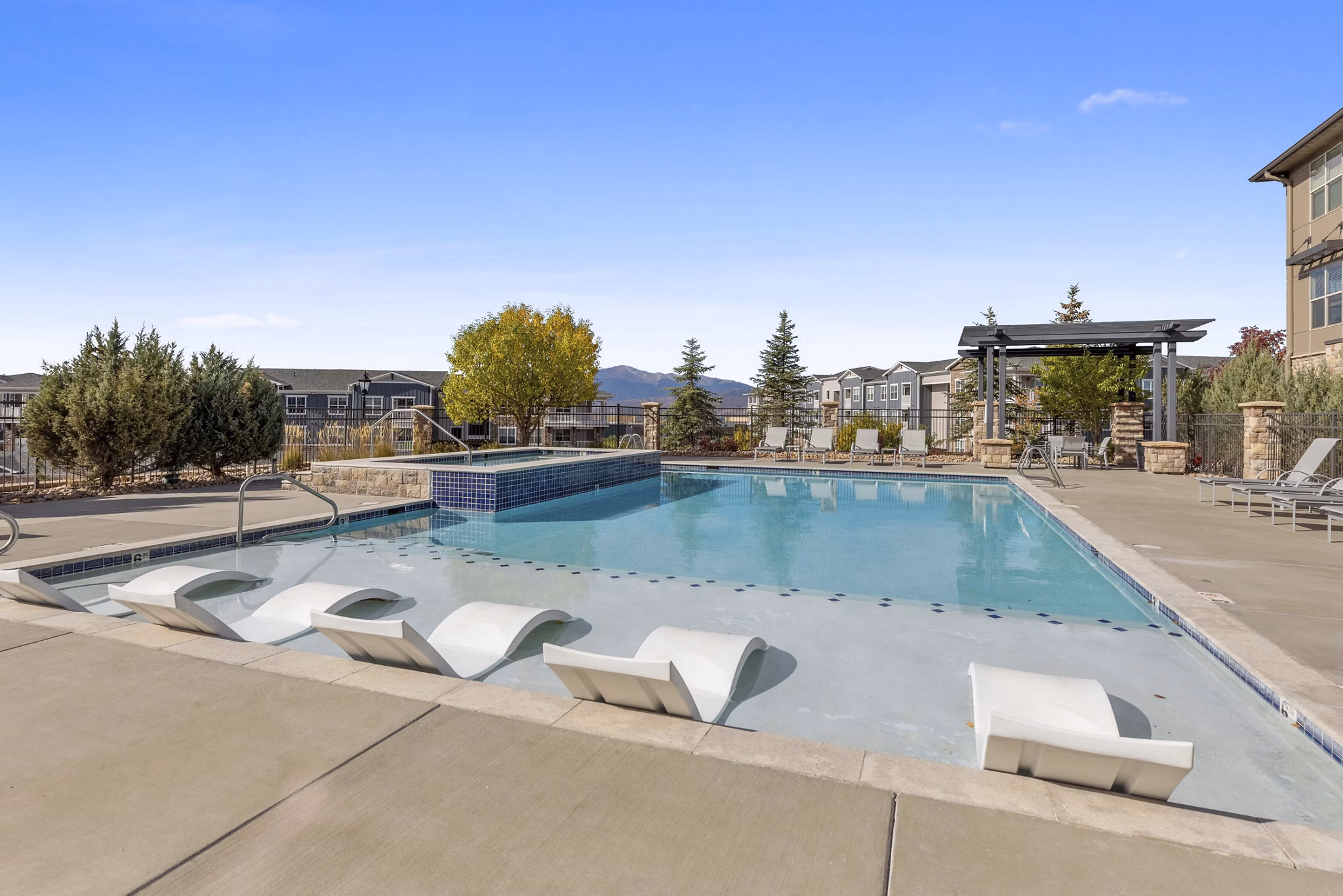 Resort-style pool at Vue 21 Apartments featuring sun loungers and palm trees