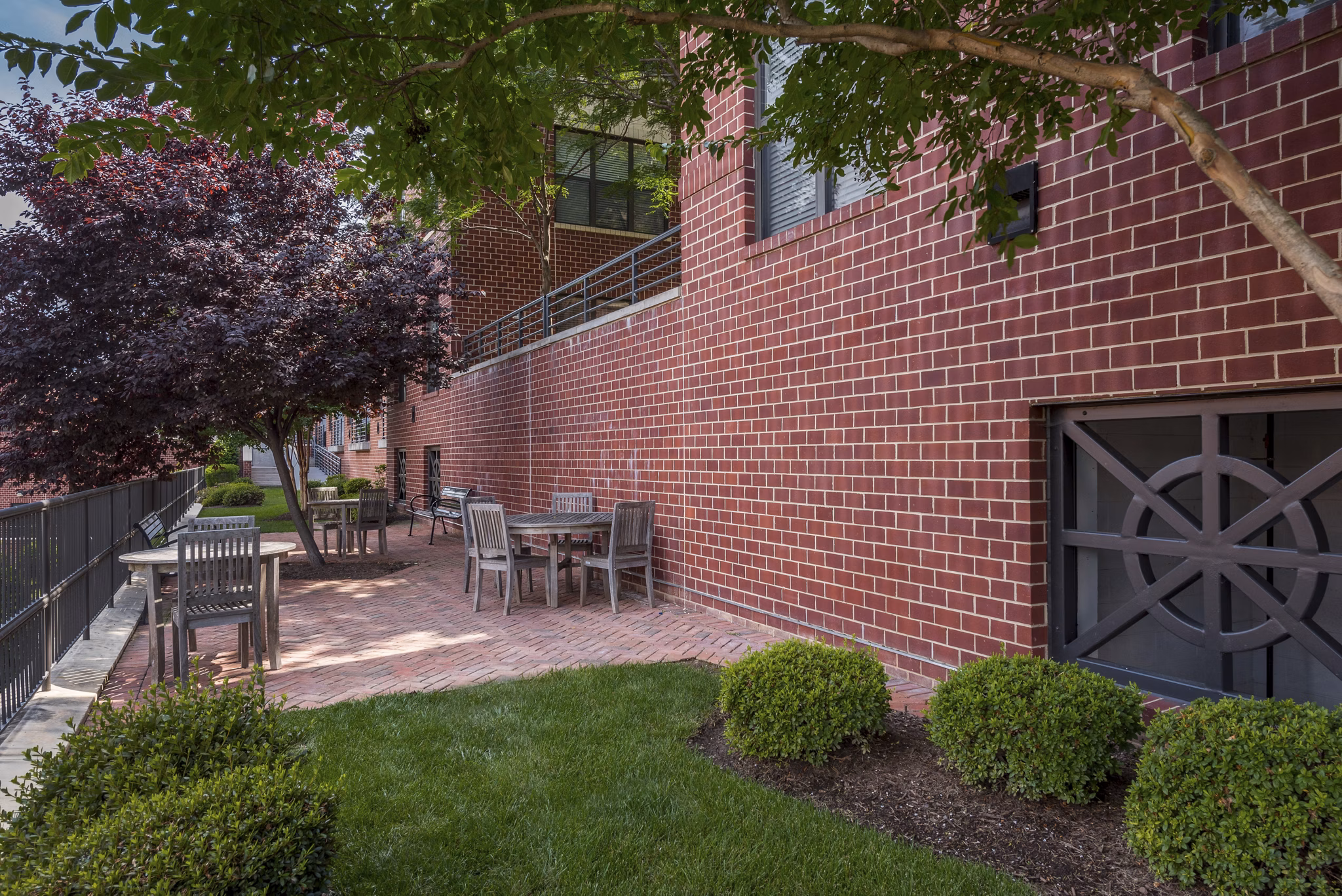 Outdoor patio with tables and chairs surrounded by landscaped greenery at luxury apartments