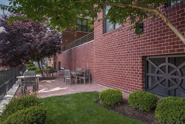 Outdoor patio with tables and chairs surrounded by landscaped greenery at luxury apartments