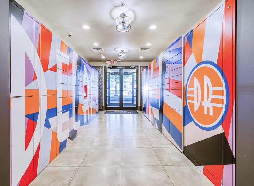 Colorful abstract wall art lining a hallway leading to a glass door in luxury apartments