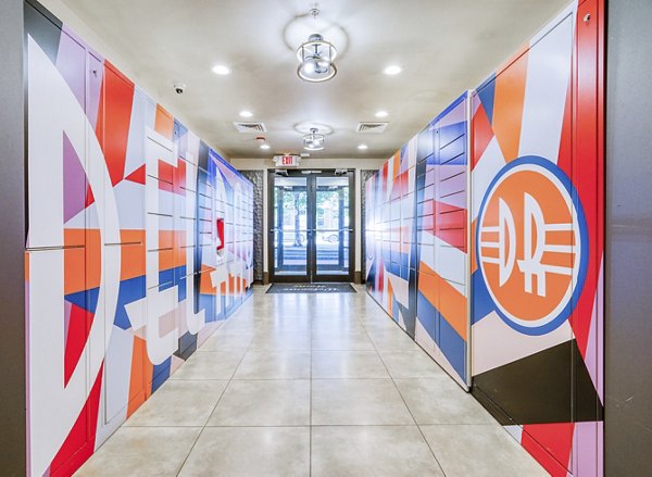 Colorful abstract wall art lining a hallway leading to a glass door in luxury apartments