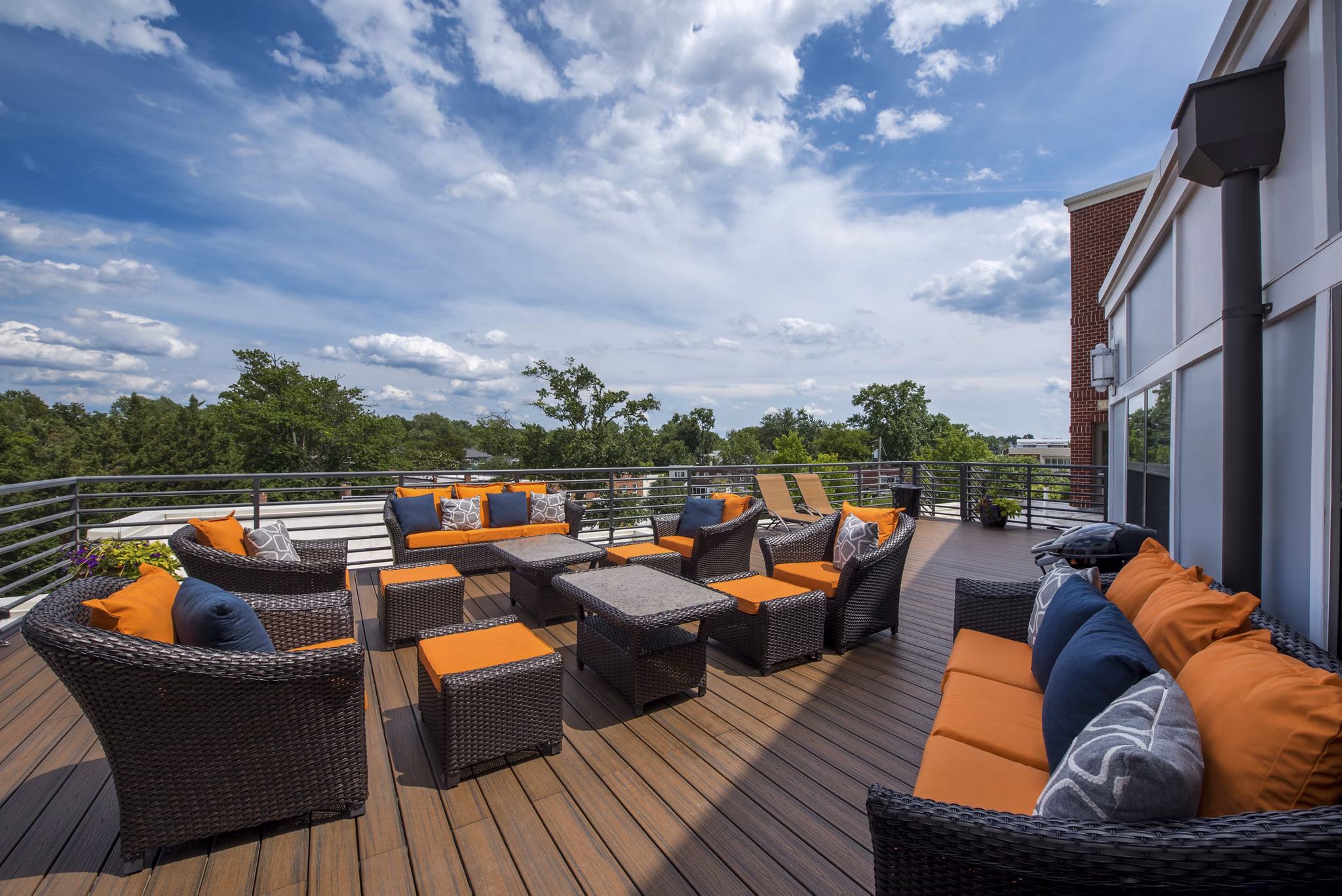Outdoor patio with wicker furniture and orange cushions in luxury apartment community