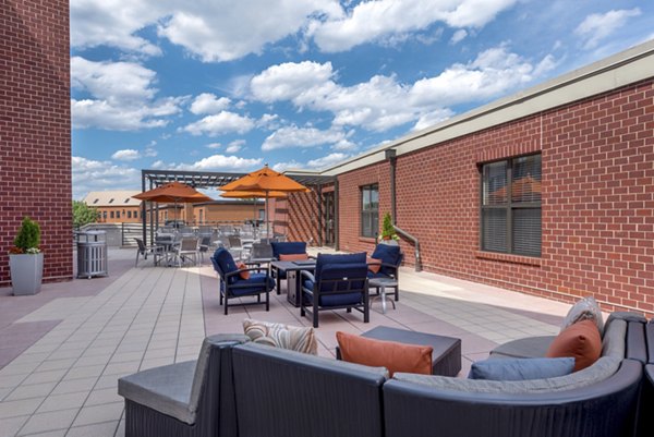 Outdoor patio area with seating and umbrellas at luxury apartments with brick buildings in the background