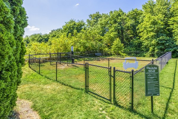 Dog-friendly park at Village at Fox Point Apartments with fenced area and agility equipment