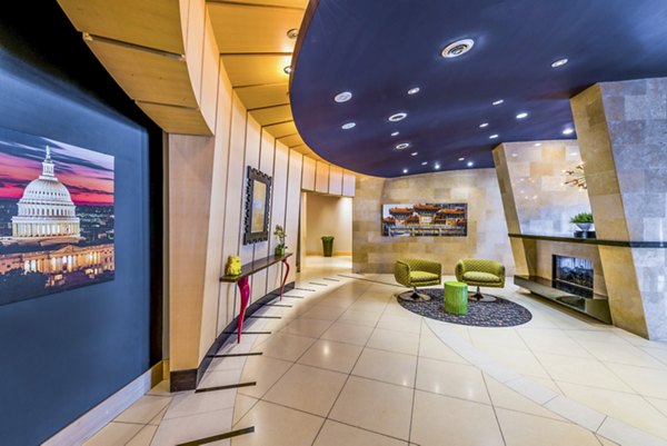 Modern lobby with curved walls, comfortable seating, a fireplace, and contemporary artwork in luxury apartments