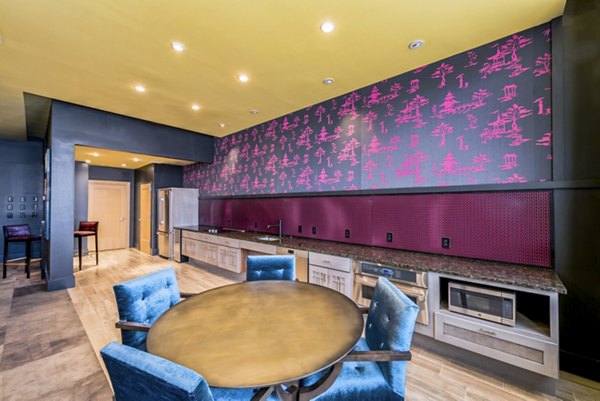 Modern kitchen and dining area featuring a round table and blue chairs with decorative pink wallpaper