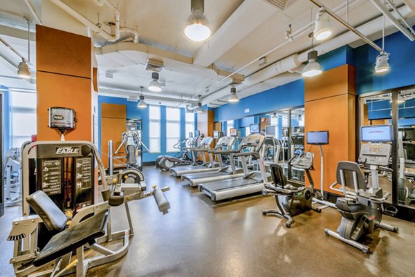 Modern gym featuring treadmills, stationary bikes, and weight machines in luxury apartments