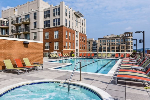 Rooftop pool area with lounge chairs and hot tub overlooking luxury apartments in a vibrant community