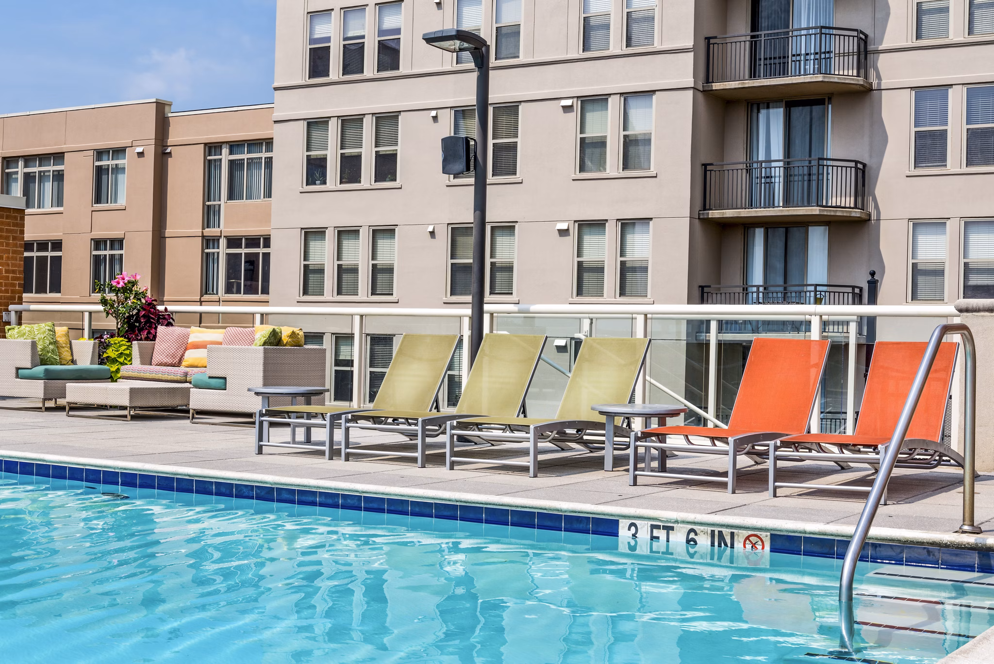 Luxury swimming pool with lounge chairs and modern apartments in the background