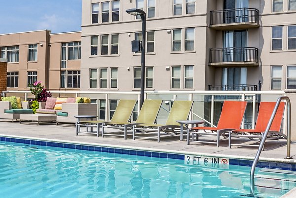 Luxury swimming pool with lounge chairs and modern apartments in the background